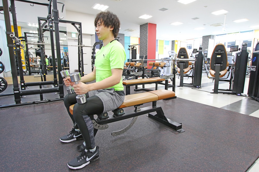 1. 両手にダンベルを持ち、膝に置いた状態でベンチに腰かける。ベンチに仰向けになり、胸の位置までダンベルを移動させます。