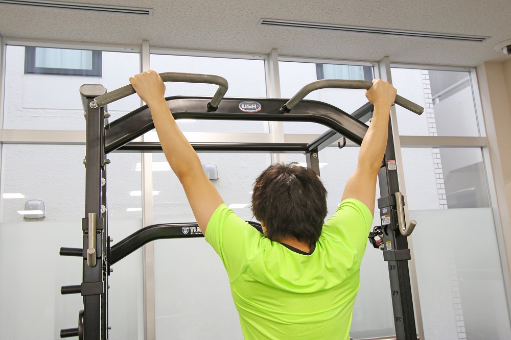 1. 両手の間隔を肩幅よりやや広めに取り、順手でバーを握る。このポジションでやりづらい場合には、両手の間隔を狭くして逆手（アンダーグリップ）にしてもよい。