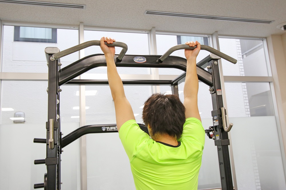 1. 両手の間隔を肩幅よりやや広めに取り、順手でバーを握る。このポジションでやりづらい場合には、両手の間隔を狭くして逆手（アンダーグリップ）にしてもよい。