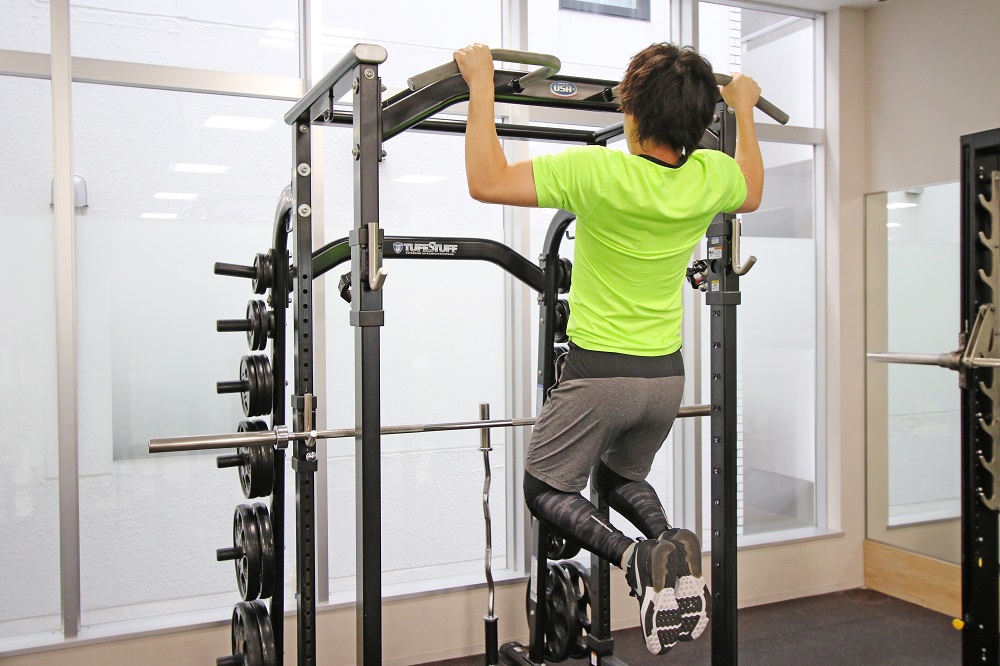 2. バーに近づけるように胸を張って、肘を背中側に引いて体を引き上げる。このとき膝は軽く曲げます。