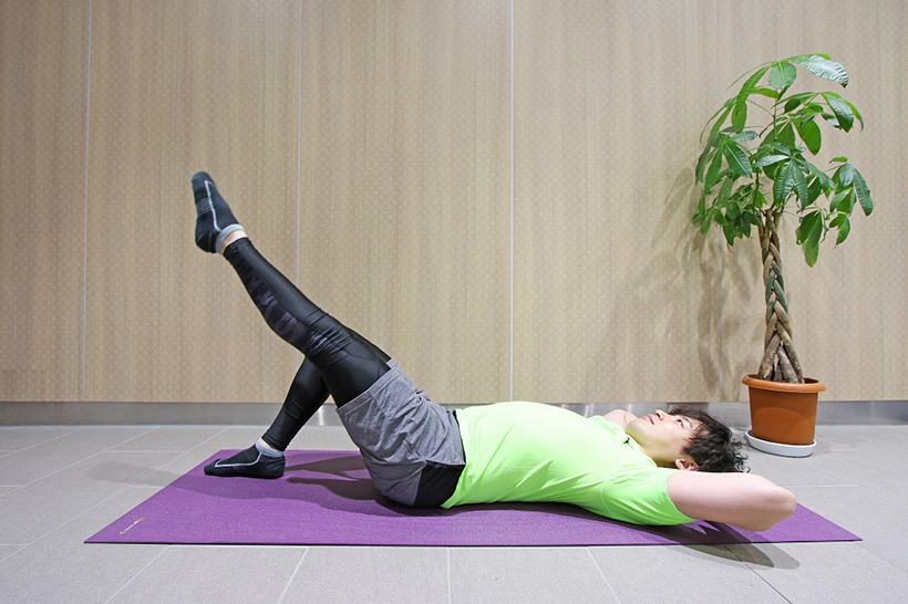 2.両手を頭の後ろで組み、頭を固定したら、片足を45度の高さまで上げましょう。まっすぐに上がるようにします。